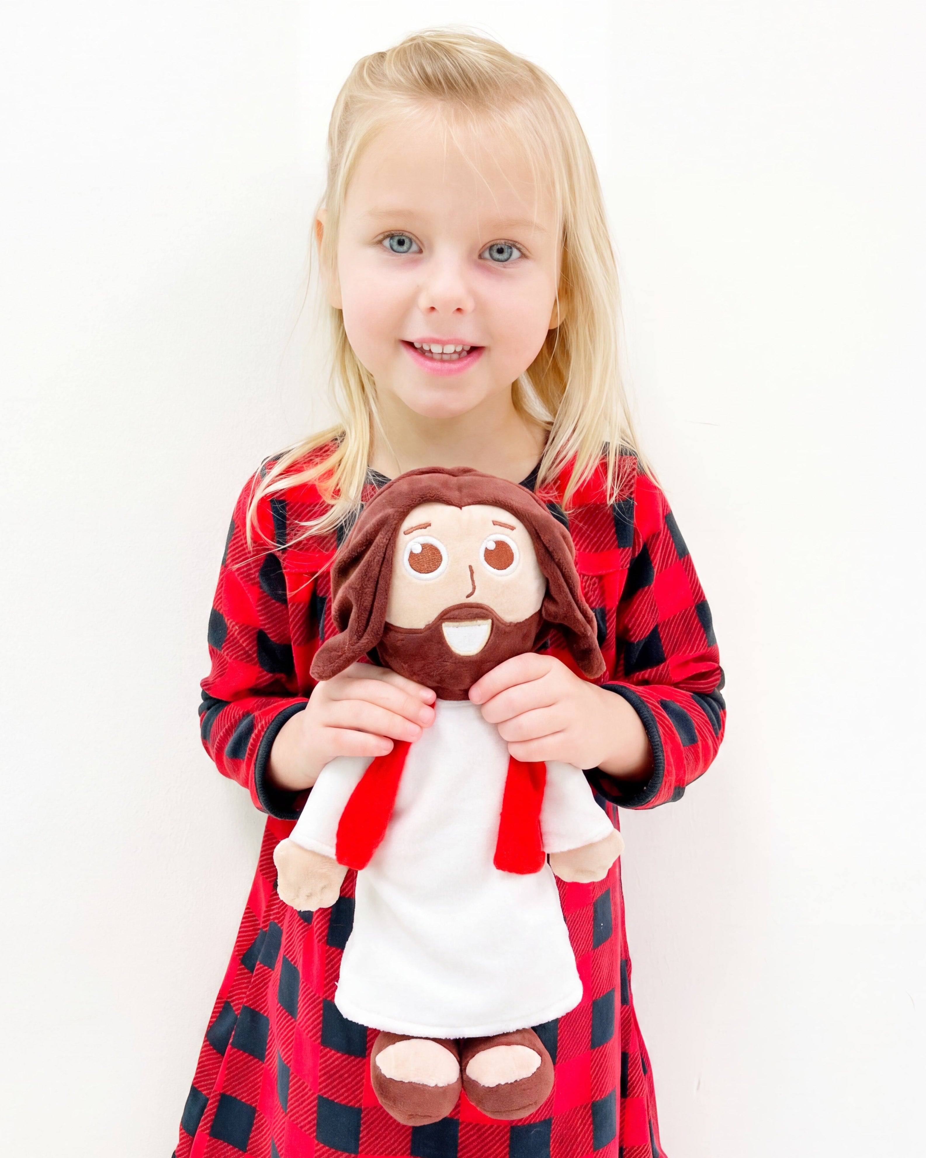 A young blonde girl wearing a red and black buffalo plaid dress holds The Talking Jesus Doll.  From Jesusdoll.com.