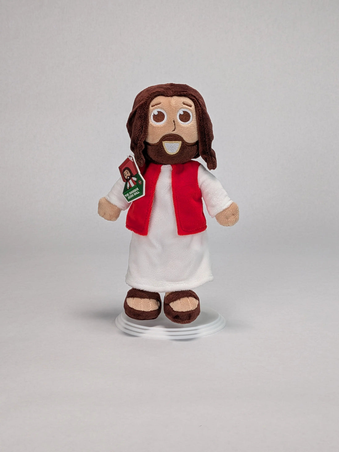 The Shoebox Jesus Doll, a plush Jesus toy from Jesusdoll.com standing in front of a light grey backgroud.